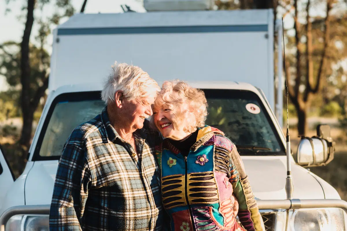 older couple smiling at each other in front of car campervan