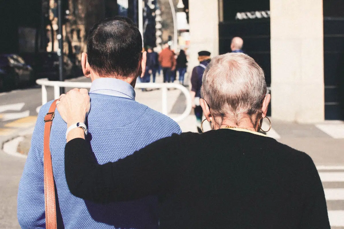 older people crossing road with arms around each other